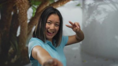 Neşeli bir şehir ortamında gülümseyen ve barış işareti yapan bir kadın güneşli bir günde gençlik enerjisini ve neşeli ruhunu somutlaştırıyor..