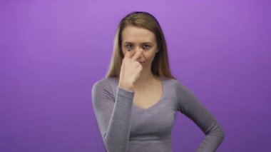 İzole edilmiş mor arka plan üzerinde ihtiyatlı hareketler yapan, genç beyaz hatlarıyla dikkat çeken, bir stüdyo ortamında odaklanmış bir görüntü yaratan bir kadın..