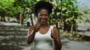 Güneşli bir parkta yeşil ağaçlarla çevrili, pozitif ve canlı bir hava yakalayan bir kadın gülümsüyor..