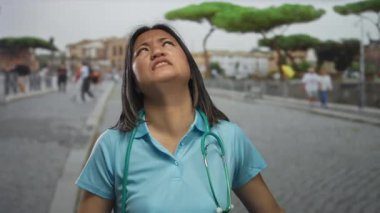 Genç Çinli kadın doktor, arka planda yürürken steteskop takarak şehir sokaklarında hayal kırıklığına uğramış hissediyor..