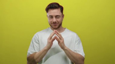 Sakallı ve beyaz gömlekli genç adam, izole edilmiş sarı arka planı dikkatlice kavradı..