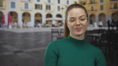 Eski şehir kafesinde gözlüklü ve yeşil kazaklı bir kadın, davetiye..