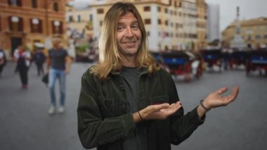 Uzun saçlı bir adam, şehir caddesinde binalar ve at arabalarıyla dolu bir yerde el sallıyor. İyimserlik..