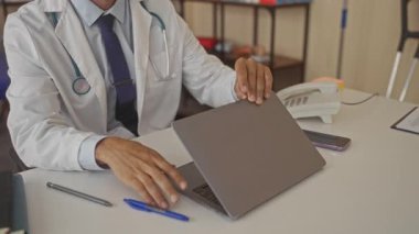 Hastane kliniğinde dizüstü bilgisayarında steteskopla yazı yazan beyaz önlüklü bir doktor. Profesyonellik..