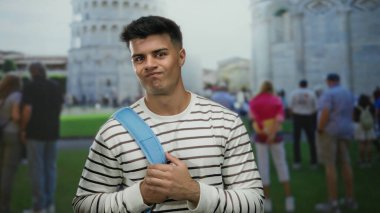 İtalya 'da sidik kulesine karşı mavi sırt çantalı genç adam çizgili tişört giyen turistlerle çevrili yazın tadını çıkarıyor..