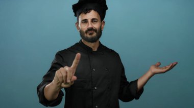 Siyah üniformalı İspanyol erkek şef mavi arka planda parmak hareketi yapmıyor..