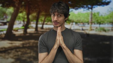 Çıplak elleriyle dua eden bir adam canlı yeşil ormandaki yapraklı ağaçların altında hareket eder. Umut..