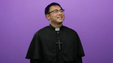 Siyah cüppeli ve çapraz kolyeli, parlak mor arkaplanlı, dinsel temayı temsil eden gözlüklü bir rahip.