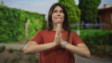 Serin bir park ortamında meditasyon yapan bir kadın, yemyeşil ağaçlar ve canlı yeşilliklerle çevrili, dua ederek sükunetini ifade ediyor..