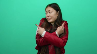 Kırmızı ceketli kadın yeşil arka planı işaret ediyor. Duygularını gösteriyor. Düşünceli, şık, çekici bir kadın..