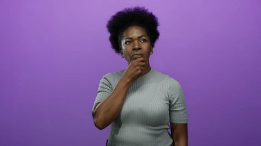 Derinden düşünen bir kadın, parlak bir mor arka plana karşı duruyor. Rahat bir tişört giyiyor. Münferit bir ortamda tefekkür ve içgözlem yansıtıyor..