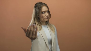 Genç kadın jestleri, izole edilmiş kahverengi duvar arkaplanına karşı eliyle buraya gelir. Davetiye ya da eylem bildirir.