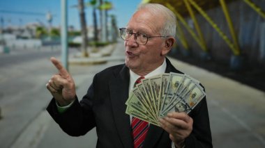 Takım elbiseli kıdemli bir adam bize dolar tutuyor, canlı bir geçmişi olan sokaklarda el kol geziyor şehir çevresini gösteriyor, zenginliği ve iş başarısını açık havada vurguluyor..