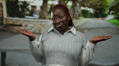 Sakin bir sokakta sıradan bir kazak giyen bir kadın şehir ortamında merak ve kararsızlık gösteriyor..