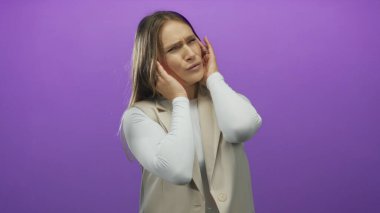 Mor arka plana karşı hayal kırıklığıyla kulaklarını tutan bir kadın gürültü bozukluğu ya da Kafkasyalı kadınların yer aldığı stres atağı kavramını öneriyor.