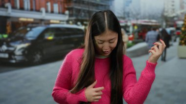 Şehirde canlı pembe süveterle gitar hareketlerini taklit eden, geçmişi bulanık bir kadın.