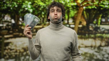 Bangladeşli yanak şişiren İspanyol bir adam parkın dışında para biriktirirken doğal ortamdaki zenginlik ve kültürel çeşitliliği vurguluyor..