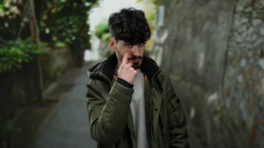 Şehir merkezindeki genç adam, şehir caddesinde dikkatli bir ifadeyle el kol hareketi yaparak açık bir çevrede tetikte olmayı ve farkındalığı öneriyor..