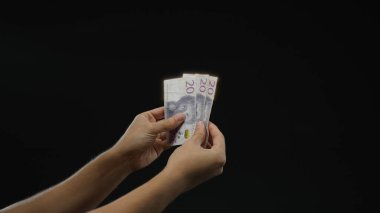 İsviçre banknotlarını izole edilmiş siyah arkaplan üzerinde tutan adam, finansal kavramları ve döviz kurunu vurguluyor.