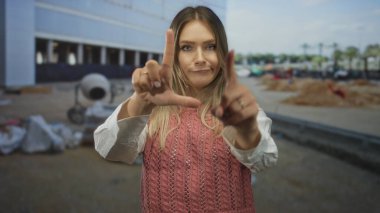 İnşaat alanında neşeli bir ifadeyle zavallı bir jest yapan kadın, çalışma ortamında gün ışığında yakalanan eğlenceli ya da mizahi bir bağlam öneriyor..