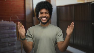 İnşaat alanında el kol hareketi yapan, kapalı alanda ölçüm yapan, günlük gömlek giyen, gülen, tuğla ve endüstriyel geçmişi olan bir adam.