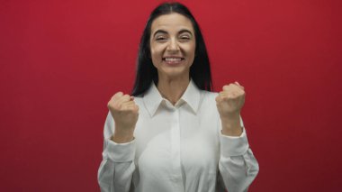 Cesur kırmızı bir duvara yaslanmış, gülümseyen ve tezahürat yapan bir kadın duygusal bir sevinç ve heyecan anı yakalıyor..