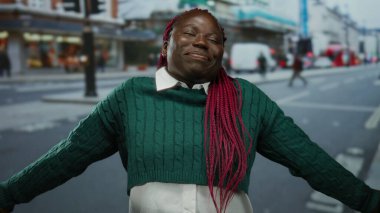 Şehir caddesinde kolları açık gülümseyen, bulanık binaları ve trafik geçmişi olan şehir yaşamını ve canlı atmosferini gösteren bir kadın..