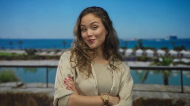 Deniz kıyısındaki bir teknenin yanında kollarını kavuşturarak gülümseyen İspanyol genç kadın, reddedilme güveni..