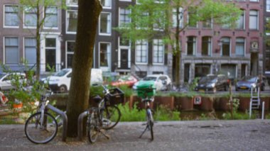 Bulanık bisikletler, çözünmüş amfi kanalı ve tarihi binaları ile Hollanda kentsel manzarasında bokeh etkisi yaratan bir ağaca dayanıyor..