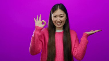 Pembe kazaklı çekici bir kadın gülümsüyor ve işaret veriyor..