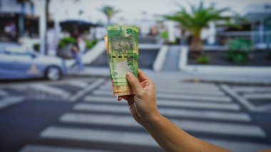 Kalabalık bir şehir caddesinde Güney Afrika rand banknotlarını elinde tutan adam canlı bir şehir ortamında iş ve para transferi kavramını gözler önüne seriyor..