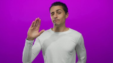 Düşünceli bir ifadeye sahip genç adam canlı pembe bir arka plana karşı duruyor, günlük beyaz bir gömlek giyiyor, izole edilmiş ve canlı bir stüdyo portresi yaratıyor..