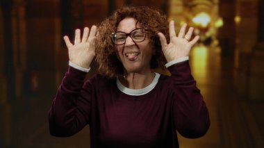 Kilisenin içinde gülümseyen esmer bir kadın orta yaşlı, canlı ışıklandırma ve günlük kıyafetlerle İspanyol bir ifade sergiliyor.