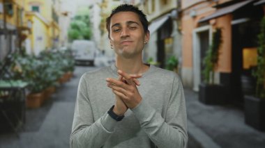 Genç İspanyol bir adam şehir sokağında dikiliyor. Bulanık bir şehir arka planında canlı ve canlı bir açık hava ortamı sergiliyor..