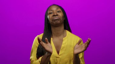 Sarı bluzlu kadın canlı pembe arka planda duruyor. Uzun örgüleri ve sakin ifadesiyle izole stüdyo ortamında kendine güveni tam bir güzellik ve tarz sergiliyor.