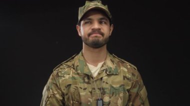 Kamuflaj üniformalı genç İspanyol adam stüdyodaki künyeyle izlemek için işaret ediyor. Dakiklik disiplini..