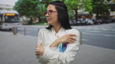 Üniformalı kadın bilimadamı arka planda bir otobüsle bir şehir sokağında durup, çevresindekilerin iç gözlem ve farkındalığını aktarıyor..