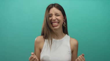 Beyaz kolsuz tişörtlü genç İspanyol kadın kulak ağrısı için kulaklarını tıkarken yüzünü buruşturuyor..