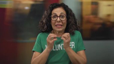 Gönüllü üniforma giyen orta yaşlı İspanyol kadın tren istasyonunda gergin bir şekilde çeneye dokunuyor..