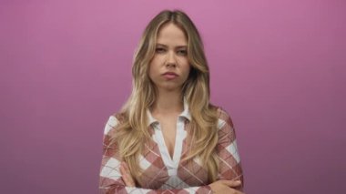 Sarışın bir kadın, stüdyo ortamında sıkılmış yumruklarını sallarken yoğun bir şekilde yüzünü buruşturuyor..