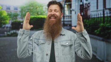 Uzun sakallı, kot ceket giyen bir adam çıplak elleriyle gülen yüzünü kaldırıyor. Kendine güveni tam..