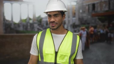 İspanyol şapkalı ve yansıtıcı yelek giyen adam, Antik Roma binasında baş parmak işareti yapıyor..