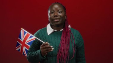 Kızıl arka planda Birleşik Krallık bayrağını tutan örgü örgülü bir kadın, İngiltere 'de ulusal gururunu sergileyen Afrikalı bir Amerikalı var..