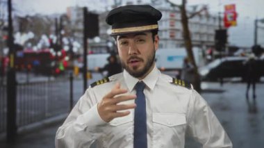 Kılavuz üniformalı, sakallı genç bir adam işlek bir sokak arka planında profesyonellik ve seyahat atmosferini aktarıyor..