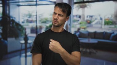 Modern otel lobisinde parmağını sallayarak hayır diyen genç bir İspanyol adam tasvip ya da anlaşmazlık içinde düşünceli ve sorgulayıcı bir atmosfer yaratıyor..