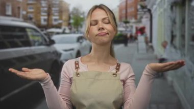 Önlüklü kadın, kalabalık bir şehir kaldırımında omuzları açık bir şekilde ayakta duruyor; şaşkınlık şüphesi belirsizlik belirsizliği belirsizlik tereddüdü, soru ikilemi, karşılaştırma.