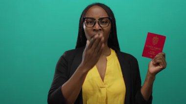 Elinde yeşil arka planı olan Norveç pasaportu tutan bir kadın, seyahat konusunda endişeli olduğunu belirtirken, sarı gömlek ve siyah ceket giyiyordu..