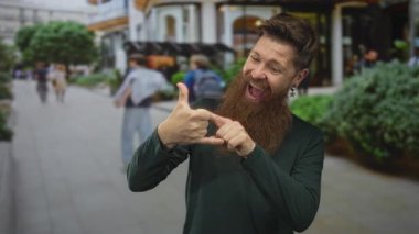 Kalın sakallı bir adam kalabalık şehir caddesinde hareketini işaret ederken enerjik bir şekilde gülümsüyor; heyecan.