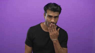 Mor stüdyo ortamında el pençe dize öpüşen genç İspanyol adam, geniş bir gülümseme; şefkat.