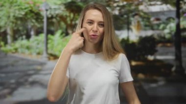 Yapraklı ağaçlar ve patikalarla çevrili yemyeşil bir açık hava parkında neşeli bir şekilde gülümseyen kadın doğada bir neşe ve rahatlama hissi taşıyor..